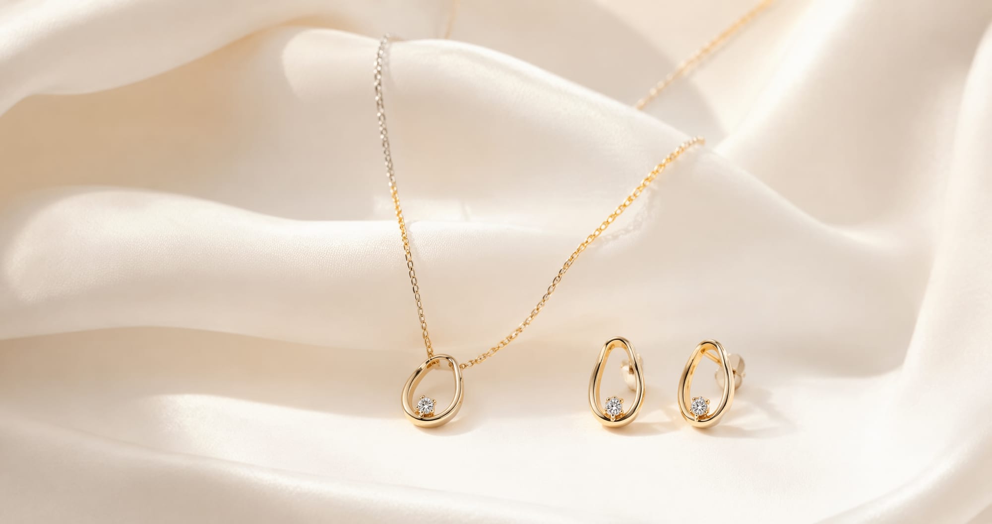 Gold pendant and earrings on cream silk